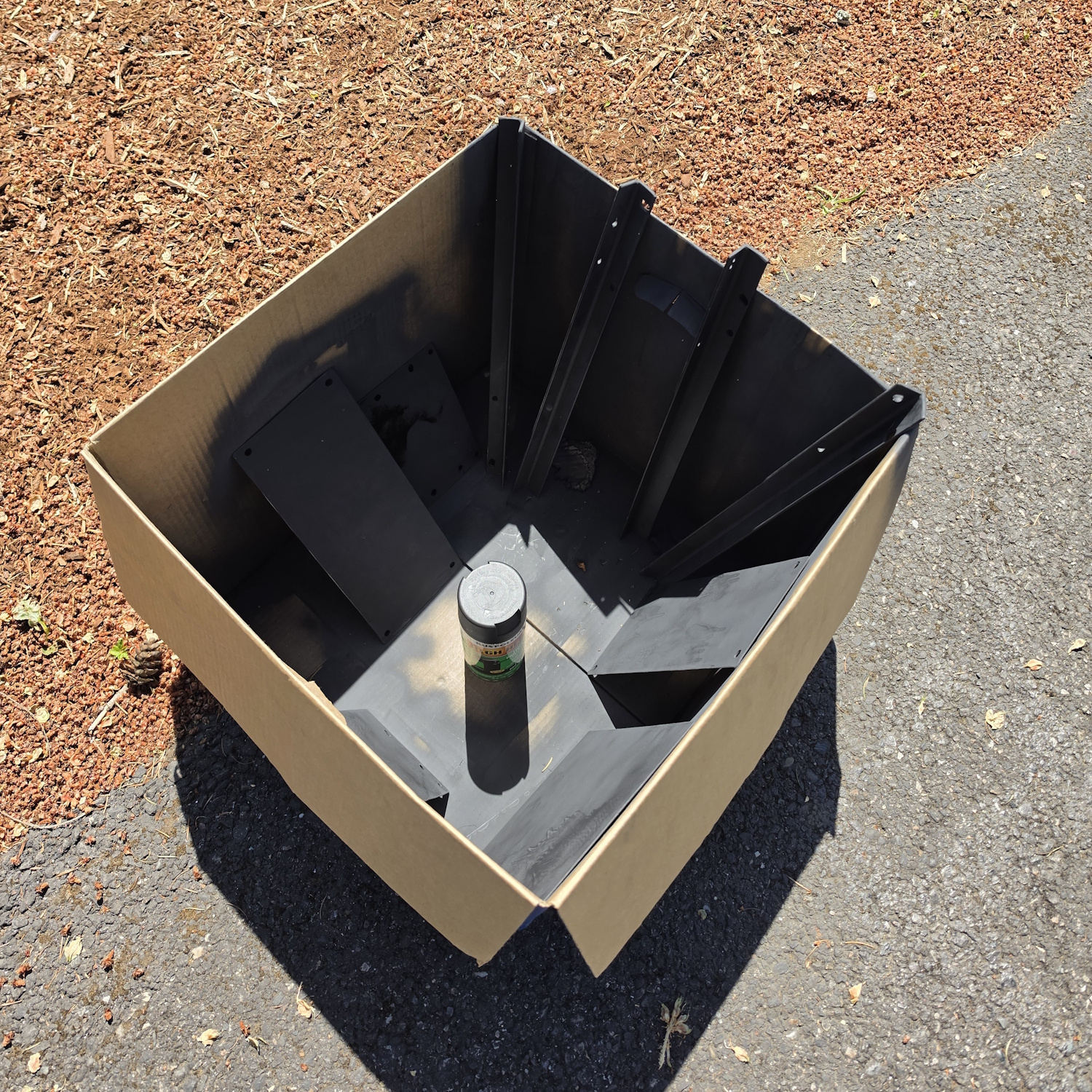 Painted firepit panels and corner posts drying in a cardboard box